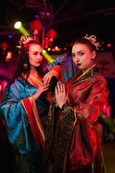 Two beautiful girls in kimono. Image of a geisha, Chinese national costume. Party concept, night club