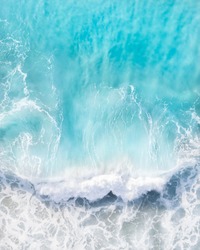 Beautiful aerial view of a wave crashing in a blue ocean during a storm