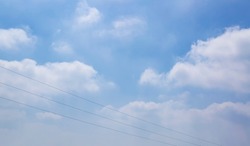 Gentle sky on the horizon. Looking up, high voltage cables against blue sky. Wide banner for electric energy industry with space for text. Calm, quiet, gentle clouds - a wide panoramic view of the sky