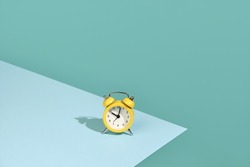 Small yellow alarm clock on a two-color background