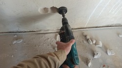 Working with a perforator. A worker drills a hole in the wall for an electrical box, close-up