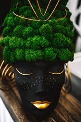 Head of a black African woman with golden lips, with hair from green vegetation