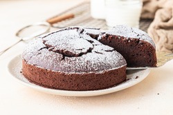 Chocolate sponge flourless cake with sugar powder, light concrete background. Brownie cake. Toned image. Selective focus