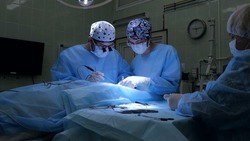 Medical team performing a surgical operation in a modern operating room. Microsurgery. Surgeon and surgeon assistant perform complex nerve repair surgery