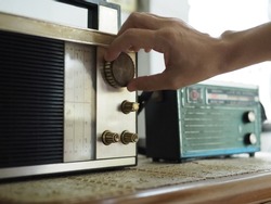 Hand tuning vintage radio with blurred background of antique transistor radio. Once upon a time concept, Nostalgic memories theme. (close up, selective focus, space for text, article layout design)
