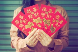 Year of the Pig or Chinese Lunar New Year celebrations theme woman holding four red envelopes with pigs image and blessing word. The Chinese words Gong Xi Fa Cai means wishing you enlarge your wealth.