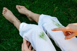 Hand showing dirty stain of grass on white pants from unexpected accident. top view. daily life stain concept. outodoors