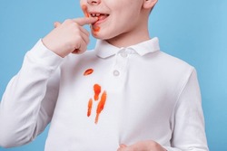 Close up stain tomato sauce spilling on white clothes. the child fingers tastes the tomato sauce. daily life stain concept. 