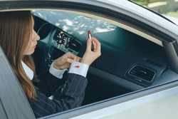 Elegant girl showing a cosmetic stain on the shirt sleeve while sitting in the car. Dirty stain of red lipstick on women's clothing. High quality photo