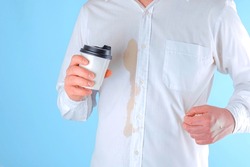 A man showing a dirty coffee stain on shirt a blue background. Spoiled clothes. Dirty coffee stain on clothes. daily life stain concept. High quality photo