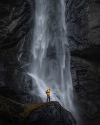 
Backpacker man in yellow jacket explores waterfall in Switzerland