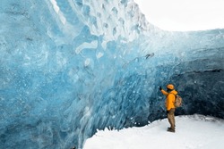 A traveler finds himself detained in an impressive landscape of ice inside the Vatnajokull National Park, in Iceland. The dazzling ice formations and intricate patterns reveal the magnificent beauty o