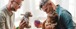 Horizontal banner or header with male gay couple with adopted baby girl at home - Two fathers playing with their daughter - Lgbtq+ family at home - Diversity concept and LGBTQ family relationship