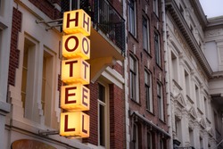 Vintage hotel sign. Luminous vertical hotel sign mounted on brick facade of hotel. Hotel in Amsterdam, The Netherlands.
