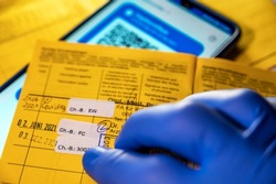 Yellow vaccination card and digital vaccination card on a smartphone