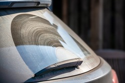 Old rear window wiper draws streaks across the rear window of a car