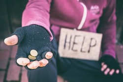 Begging hand with single coins and cardboard sign with inscription Help