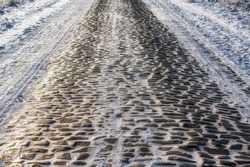 Mirror-smooth road surface of a cobblestone road with subsoil of ice and snow