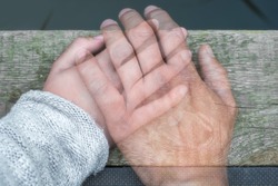 Semi-transparent man's hand on a woman's hand as a sign of farewell by separation or death