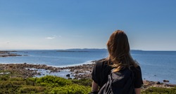 Woman standing and looking at the ocean on Hallands Vadero island in southern Sweden during summer. 
