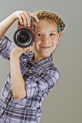 Beautiful little girl photographed on mirror camera on gray background.