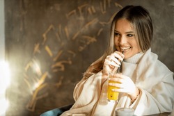 Beautifull young girl drinking an orange juice and smiling in caffe
