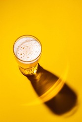 Glass of light beer on a yellow background, top view. Shadow from a glass of lager. 