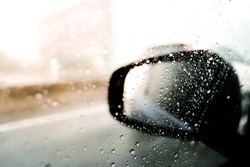 Blurred,Rain drops on a car window with the mirror in the background