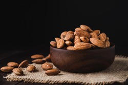 Almonds in a wooden bowl on dark wooden table, Almond  background with copy space