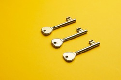 Simple door keys organized in a row over bright yellow background