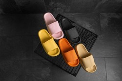 Black, pink, yellow, orange Sandals shoes. Colorful flip flops on dark black background. Isolated shoes