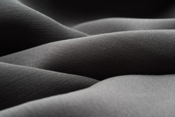 Macro photography of silk gray fabric, texture. Luxurious dark sewing background. Beautiful shiny satin fabric, close-up, copy space. Abstract, minimalism, monochrome.