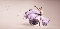 Woman dancing in flowing purple dress in studio