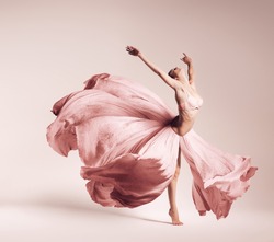 ballerina dancing in flowing pink dress in studio