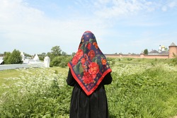 Russian tourist woman in traditional national Pavlovo Posad folk shawl, Pavloposadsky scarf. Kremlin in Suzdal town, Vladimir region, Russia. Travel, tourism in Russia. Russian style. Suzdal landmark