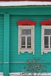 Ornamental window with carved frame on vintage green wooden rural house in Maydakovo village, Ivanovo region, Russia. Building facade. Russian traditional national folk style in wooden architecture