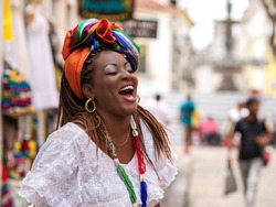 Happy Brazilian woman of African descent dressed in traditional Baiana costumes in the Historic Center of Salvador da Bahia, Brazil.
