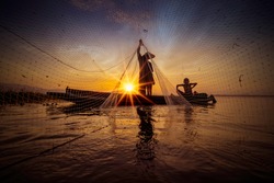 Image is silhouette. Fishermen Casting are going out to fish early in the morning with wooden boats, old lanterns and nets. Concept Fisherman's life style