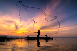 Image is silhouette. Fishermen Casting are going out to fish early in the morning with wooden boats, old lanterns and nets. Concept Fisherman's life style.
