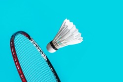 Shuttle cock badminton and racket in the blue background.