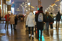People walking at the winter night Moscow street. Back, rear view. Illuminated the capital of Russian Federation.