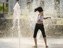 Pretty young woman playing with cold water of dry fountain. She having fun and happy.  Hot summer amusement. Lifestyle concept. Back, rear view