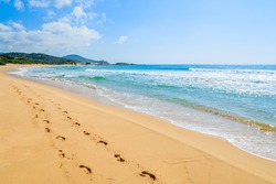 Footprints on beautiful sandy Chia beach and turquoise sea water, Sardinia island, Italy
