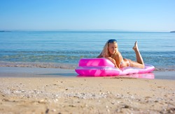 Blonde girl swimming on mattress in the sea