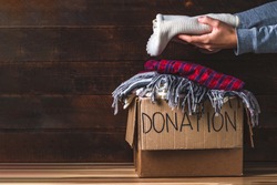 Donation concept. Donation box with donation clothes on a wooden background. Charity. Helping poor and needy people. Copy space 