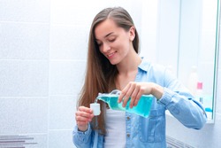 Happy smiling healthy young woman using in bathroom a mouthwash gel to rinsing mouth, fresh breath, dental and gums health. Oral hygiene and teeth care 