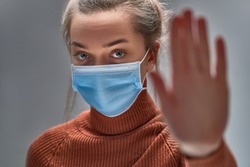Stop the virus and epidemic diseases. Healthy woman in blue medical protective mask showing gesture stop. Health protection and prevention during flu and infectious outbreak