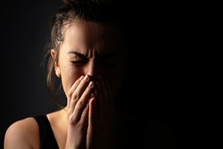 Sad grieving crying female with folded hands and tears eyes on a dark black background during trouble, life difficulties, loss and emotional problems. Copy space 