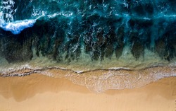 Abstract drone view taken directly from above of some tidal waves breaking along the shoreline of a beach in Bali Indonesia.