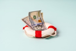 A lifebuoy with banknotes lie on a blue background, the concept of assistance and security in finance